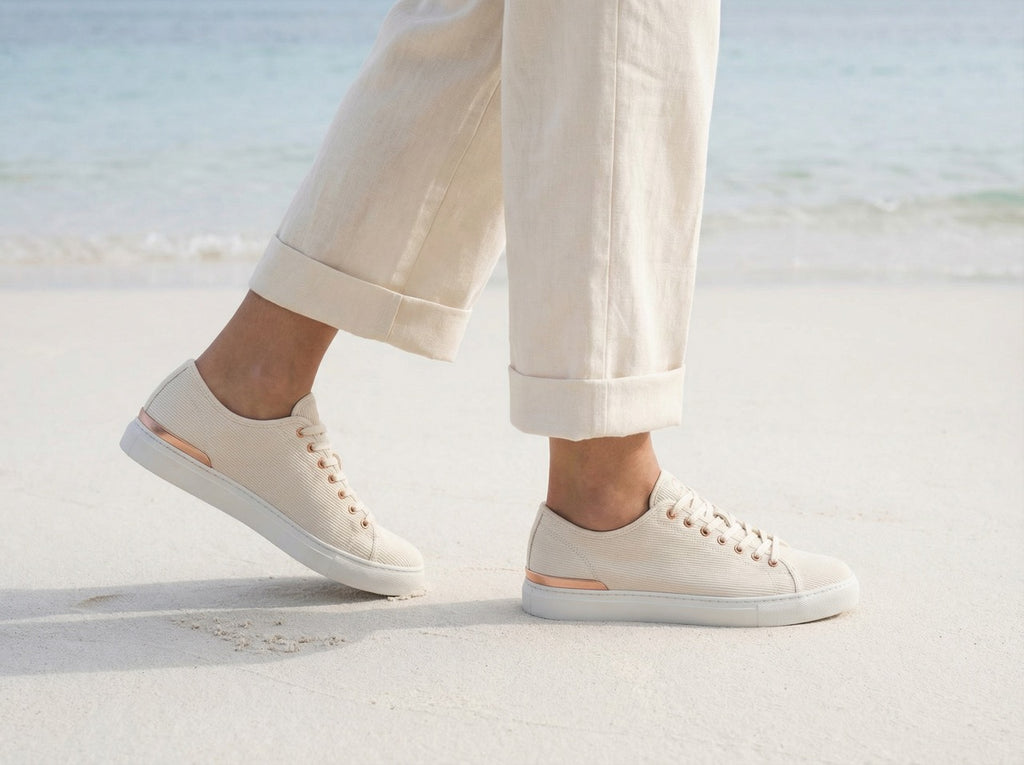 White ERTH CLASX sandstone sneakers worn with light-colored pants on a sandy surface